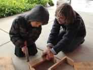 child using a hammer to build a bird feeder