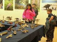 people examining wooden birds displayed on a table